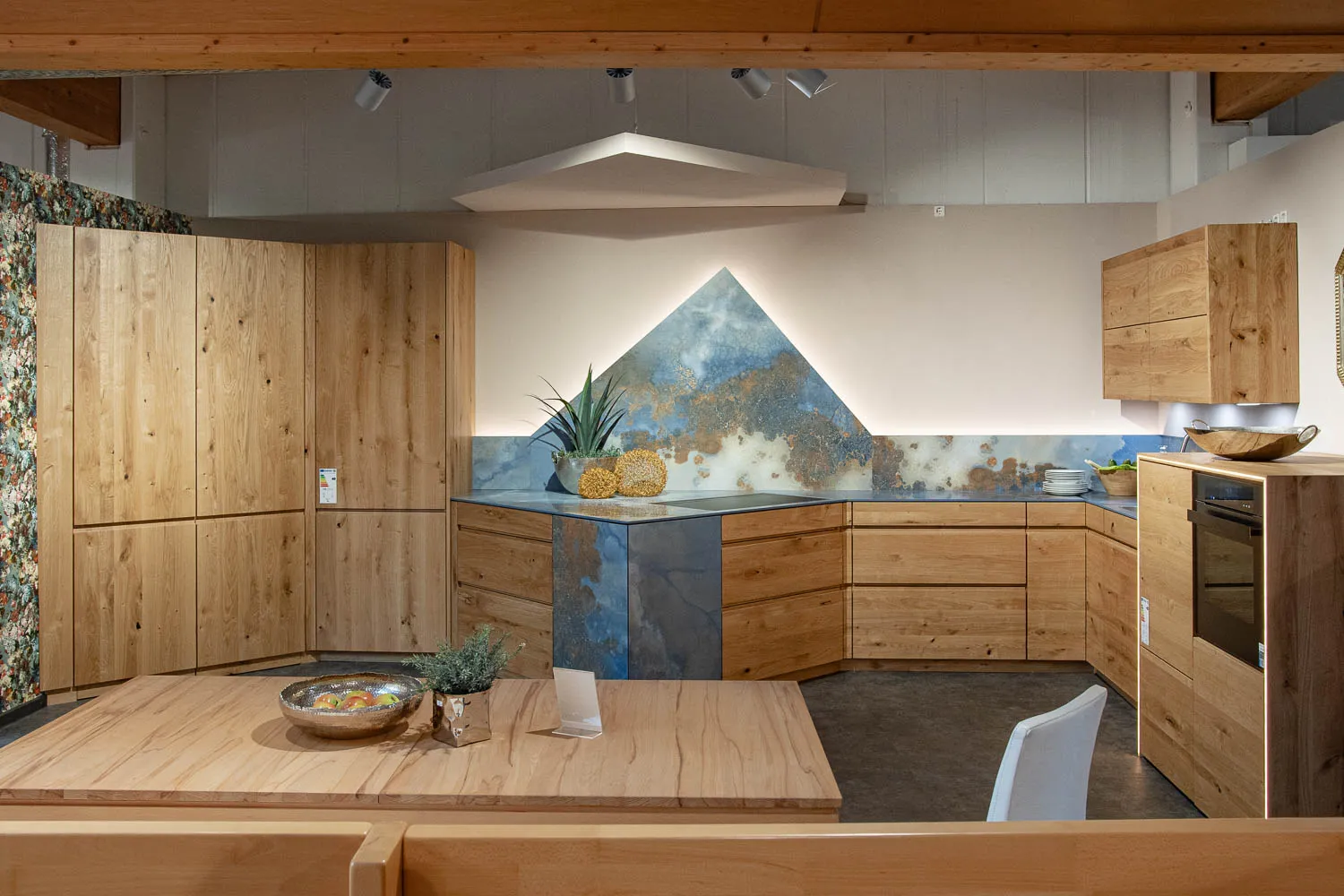 Massivholz-Eckküche mit blauer Natursteinwand in der Ausstellung Großheubach